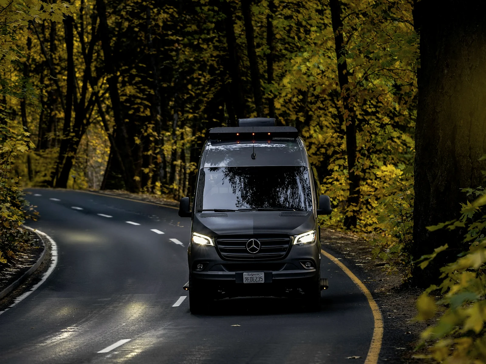 Mercedes-Benz Sprinter Camper auf einer Waldstraße im Herbst